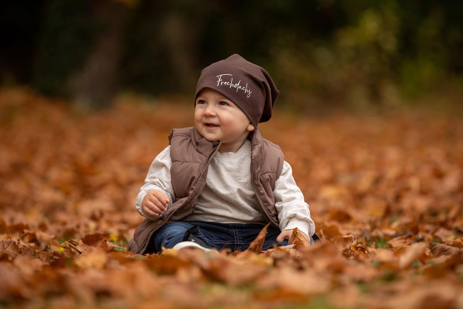 Ein Kind mitten in buntem Herbstlaub beim Babyshooting