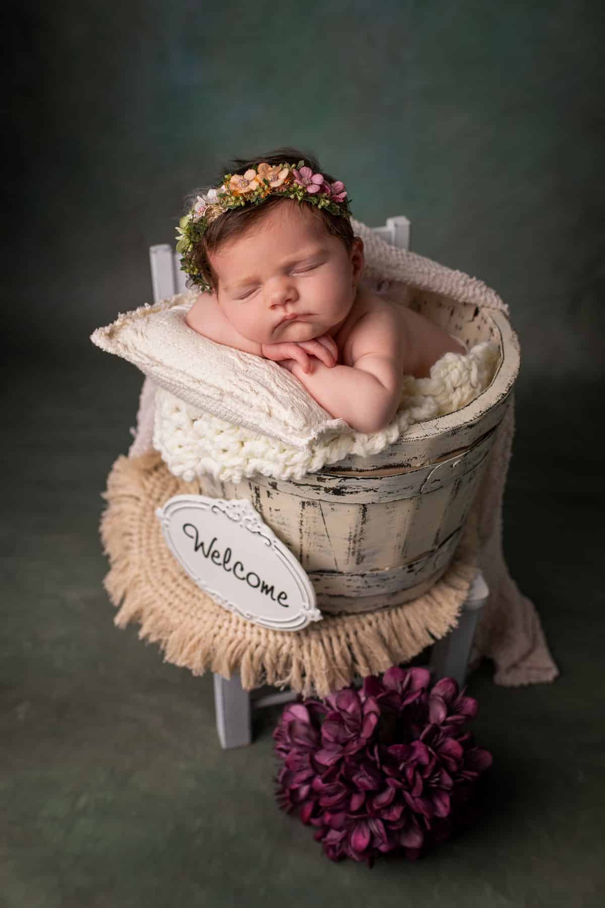 Ein Baby mit Blumenkranz im Haar schläft in einem Korb